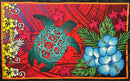 A flat-lay view of the Hibiscus, Plumeria Assortment Sarong (Style 10) featuring a vibrant Polynesian-inspired design. The pattern includes three large, bright blue hibiscus flowers and smaller pink plumeria blossoms set against a vivid red background. The design is dominated by a large, intricately detailed teal sea turtle (honu) with swirling shell patterns, surrounded by traditional tribal motifs, stylized green leaves, and a yellow geometric border on the left side.