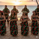 Polynesian dance group wearing tropical floral attire in black, red, and green Hibiscus Plumeria print cotton fabric on a beach.