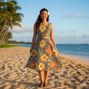 A smiling woman standing on a tropical sandy beach with palm trees, wearing a sleeveless A-line summer dress featuring the Hibiscus on traditional Tapa Polyester Fabric in the yellow colorway