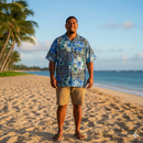 A Samoan man smiling on a tropical beach at sunset, wearing a custom button-down Aloha shirt tailored from Hibiscus on traditional Tapa Polyester Fabric in the Royal Blue colorway.